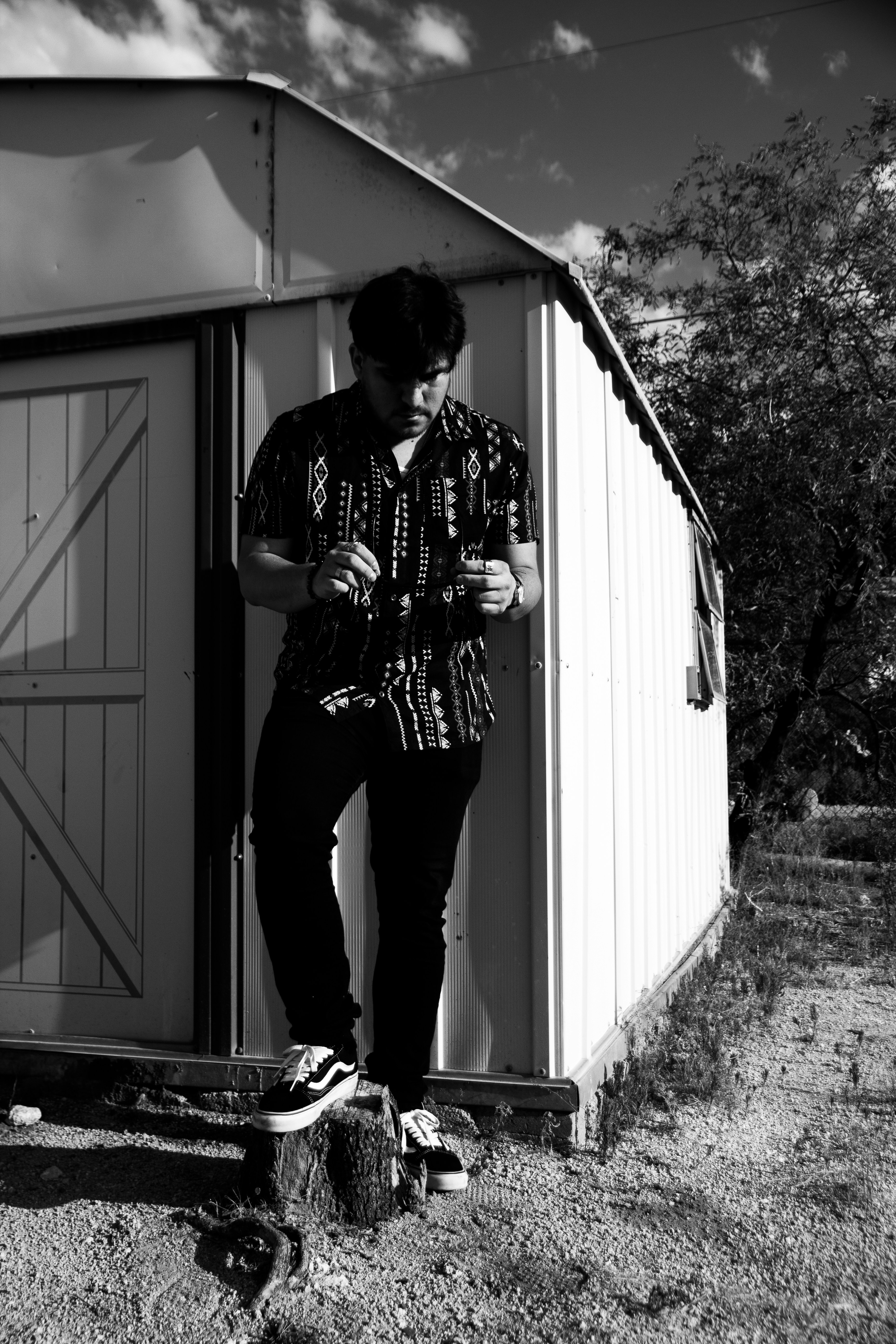 man in black and white plaid dress shirt and black pants standing beside white wooden door