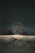 silver round coin on brown concrete surface