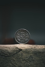 silver round coin on brown concrete surface