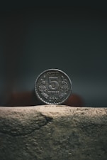 silver round coin on brown concrete surface