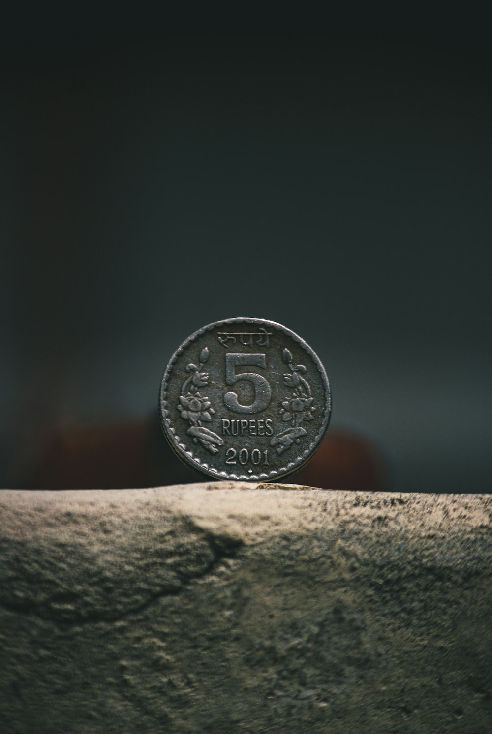 silver round coin on brown concrete surface