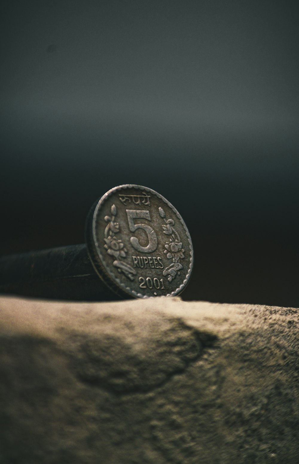 gold round coin on brown rock