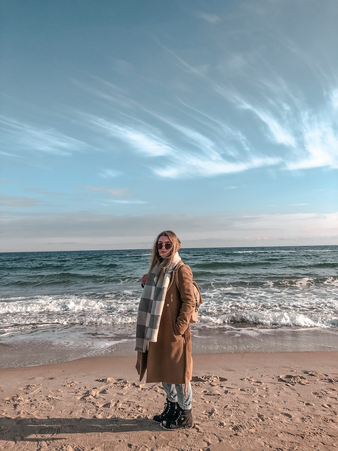 woman in brown coat standing on beach during daytime