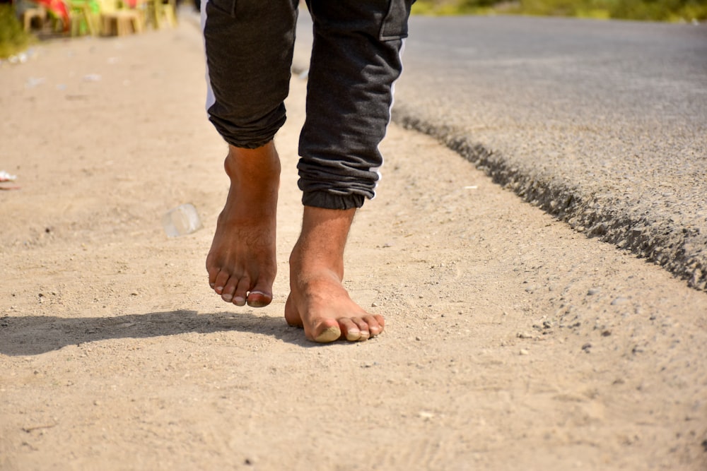 Person in schwarzen Jeans, die tagsüber auf grauem Betonboden steht