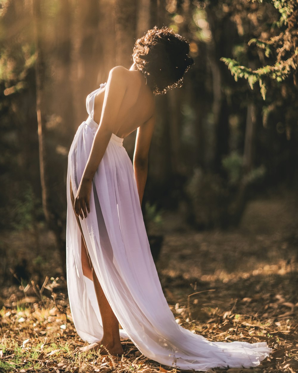 woman in white dress standing on brown dried leaves during daytime