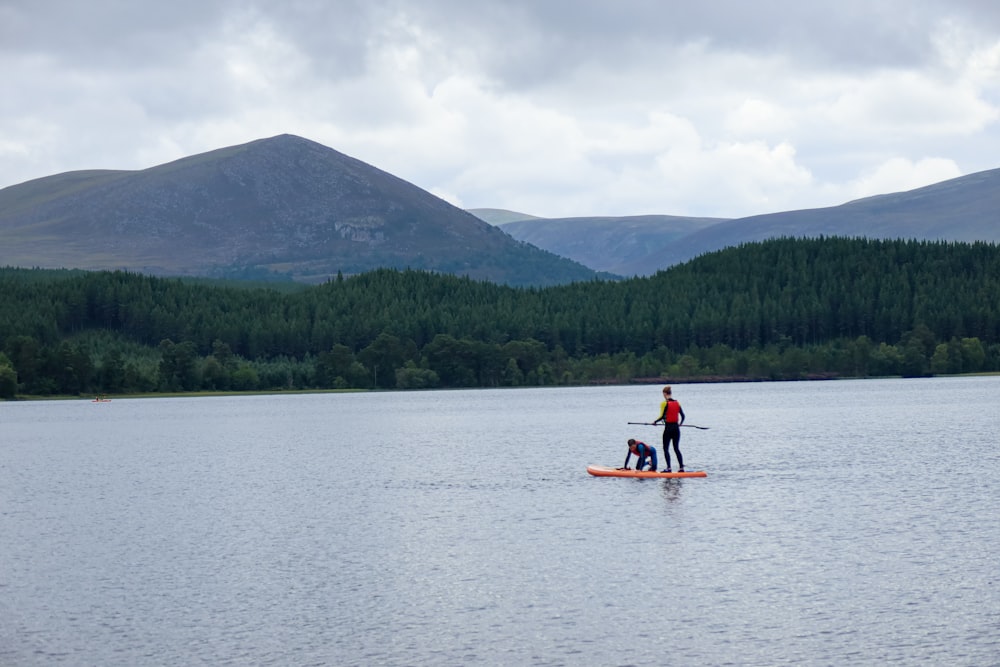 2 personas montando en kayak en el lago durante el día