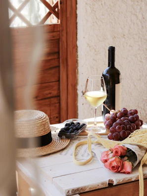 Close-up of a rustic wooden table with several bottles of red and white Puglian wine surrounded by grape clusters.