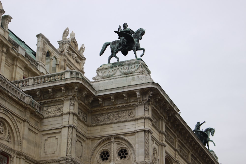 man riding horse statue in front of beige concrete building