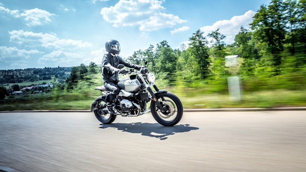 A close-up of a red and black motorcycle speeding on a winding road under a clear blue sky.