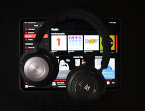 A serene scene of headphones and a softly glowing tablet displaying worship and lullaby music playlists.