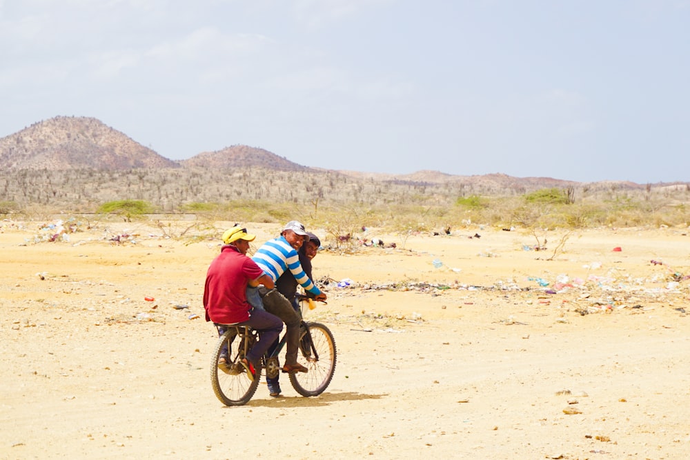 Mann in blauer Jacke fährt tagsüber Fahrrad auf braunem Sand