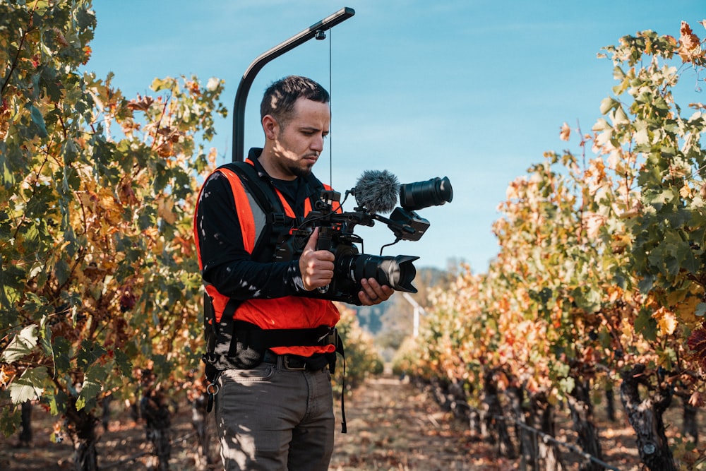 man in black and red jacket holding black dslr camera