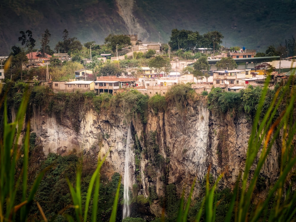 edifícios de concreto branco e marrom perto de árvores verdes e montanha durante o dia