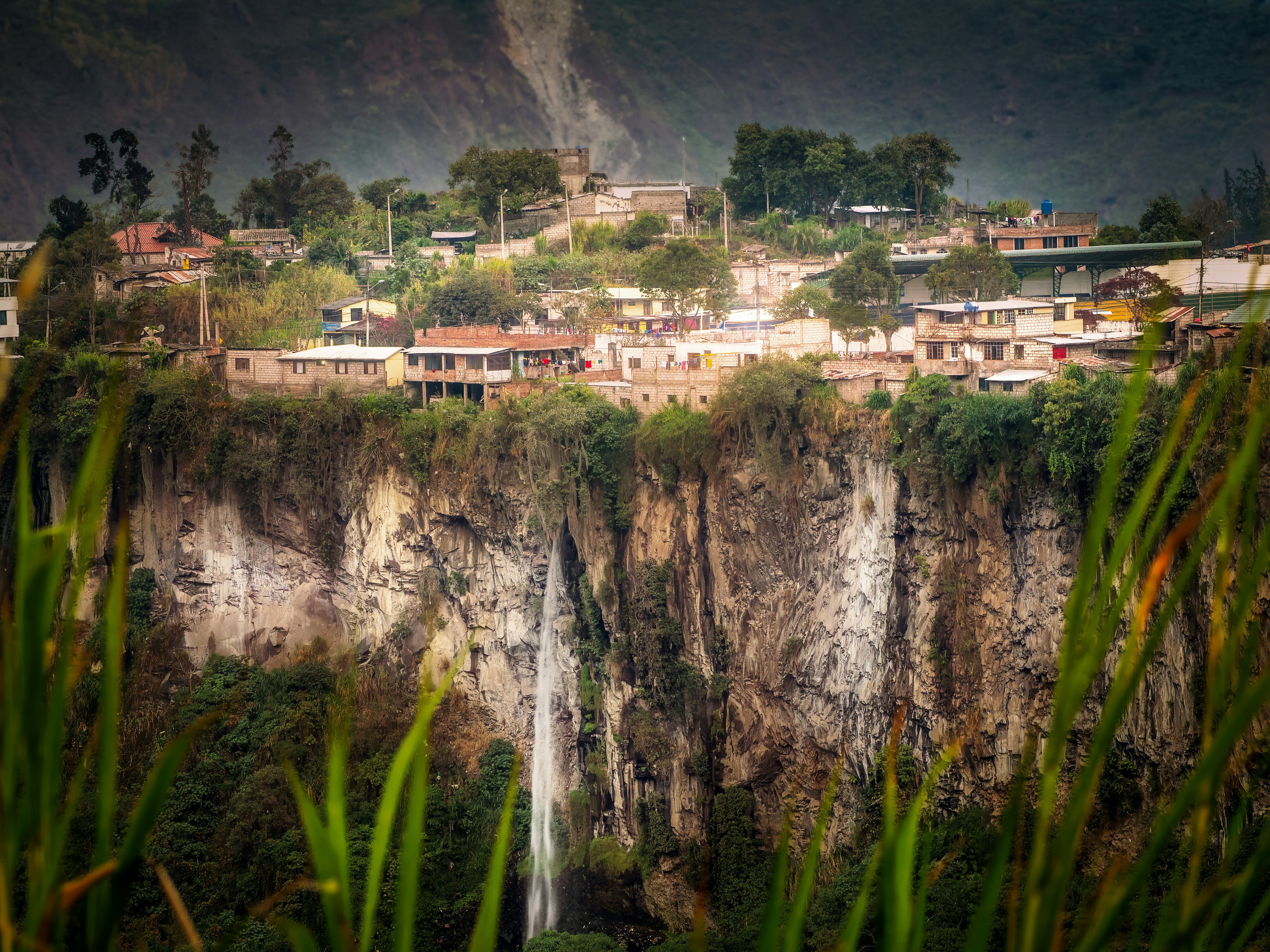 white and brown concrete buildings near green trees and mountain during daytime