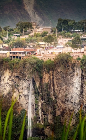 white and brown concrete buildings near green trees and mountain during daytime