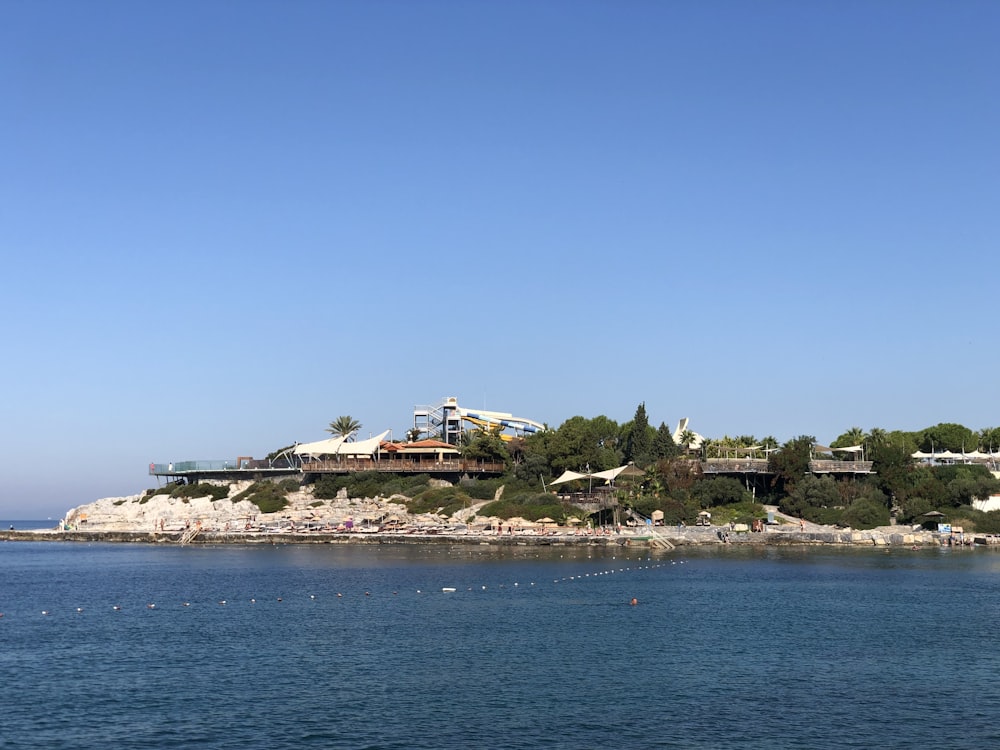 white and brown house on island surrounded by water under blue sky during daytime