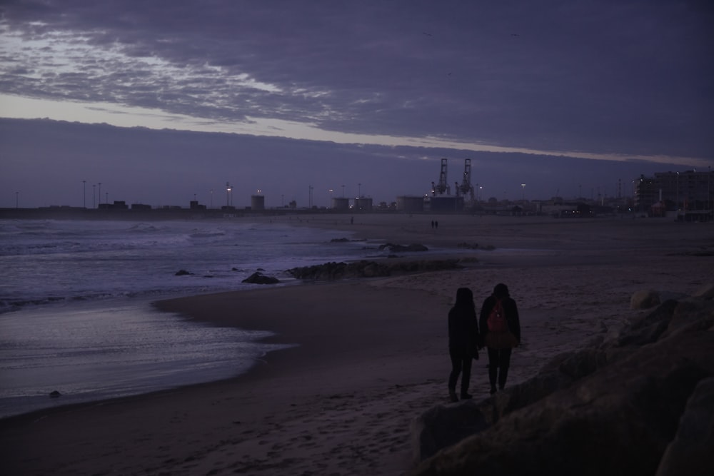 silhouette of man and woman standing on seashore during daytime