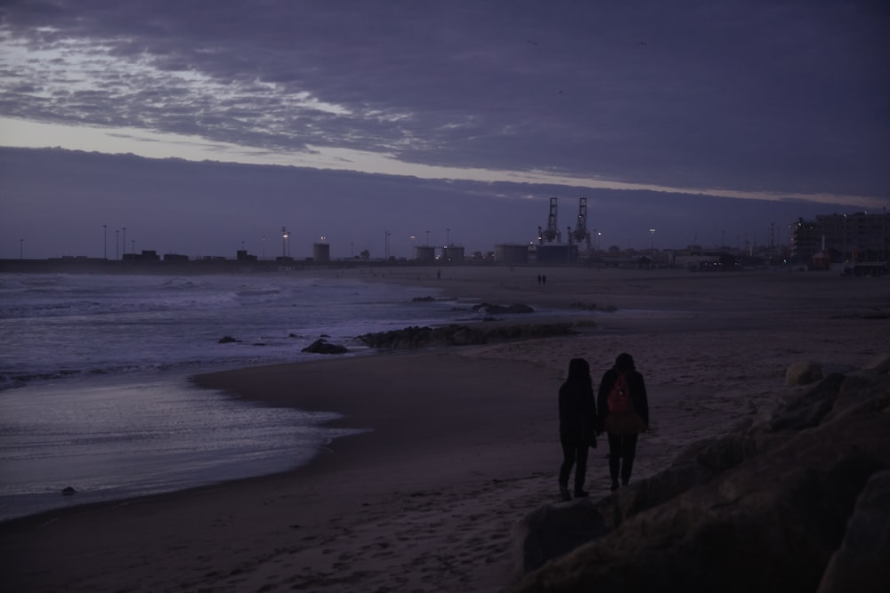 silhouette d’homme et de femme debout sur le bord de mer pendant la journée