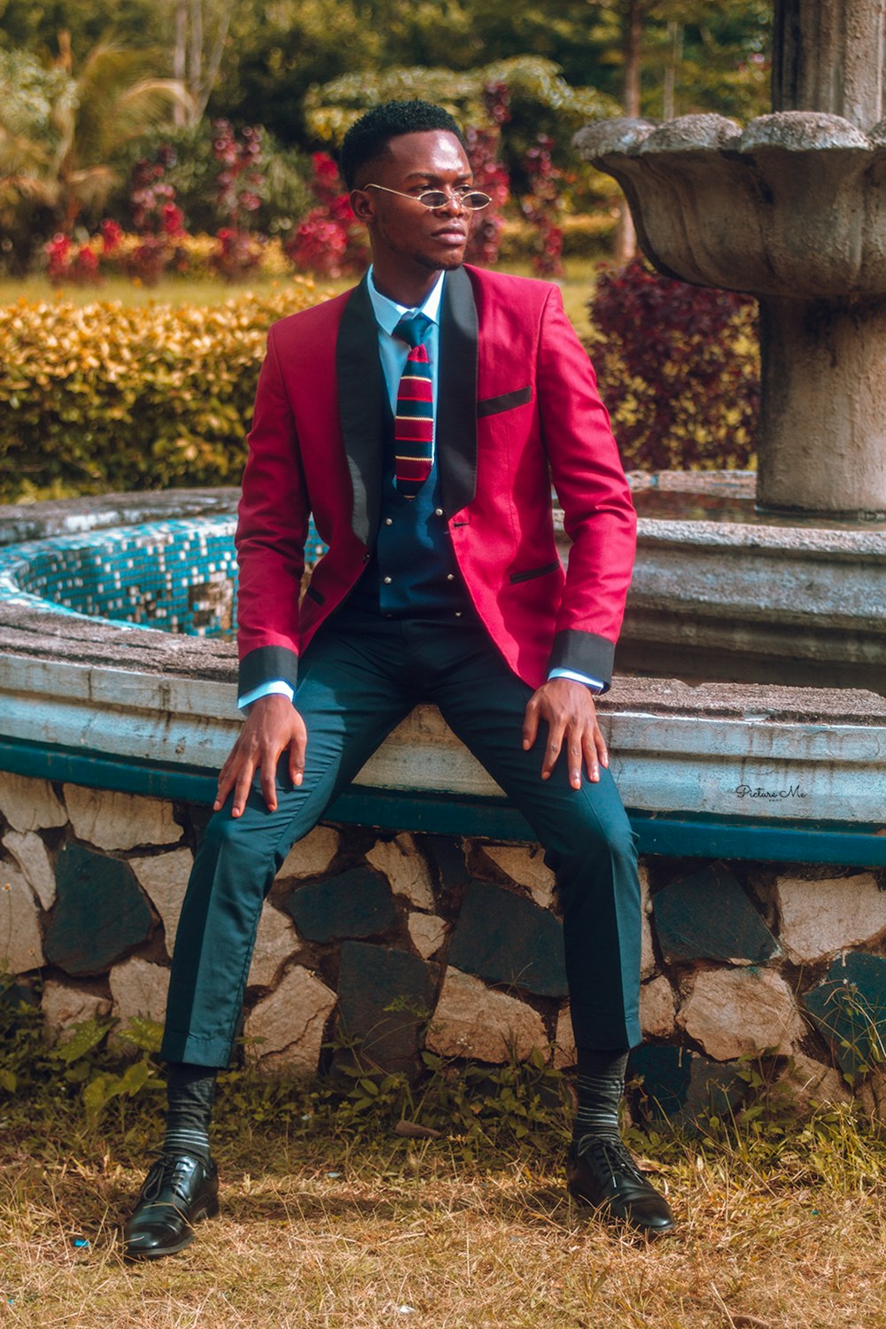 man in red blazer sitting on concrete stairs