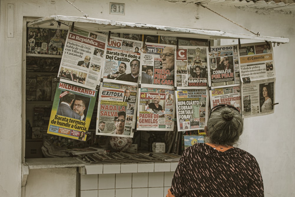 uma mulher em pé na frente de uma banca de jornal