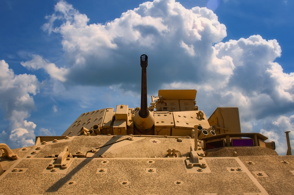 brown battle tank on brown sand under white clouds and blue sky during daytime