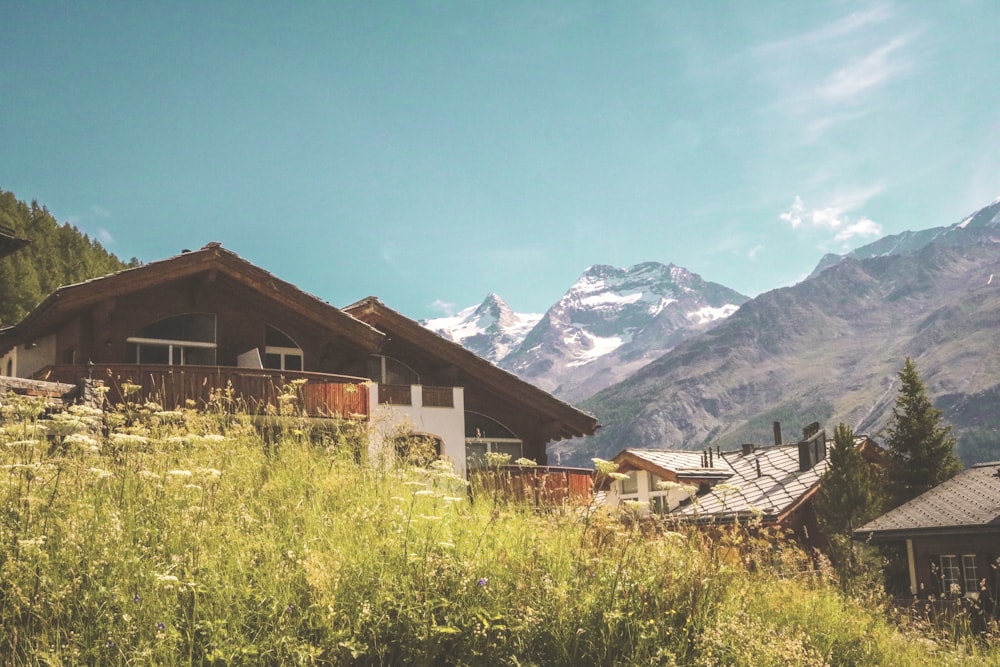 brown wooden house near snow covered mountains during daytime