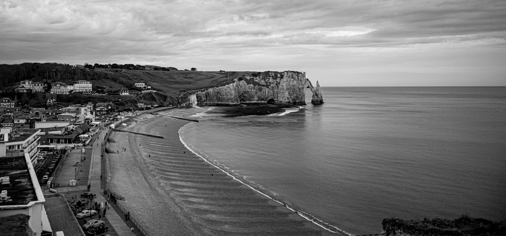 grayscale photo of sea near mountain