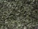 A close-up view of dried green herbs and leaves, showing a mix of finely chopped and crumbled pieces with a textured and natural appearance.