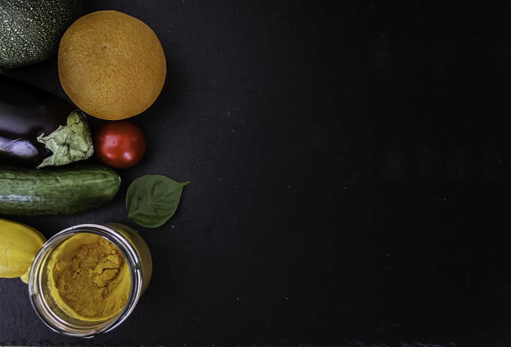 orangefarbene Frucht neben grünen runden Früchten