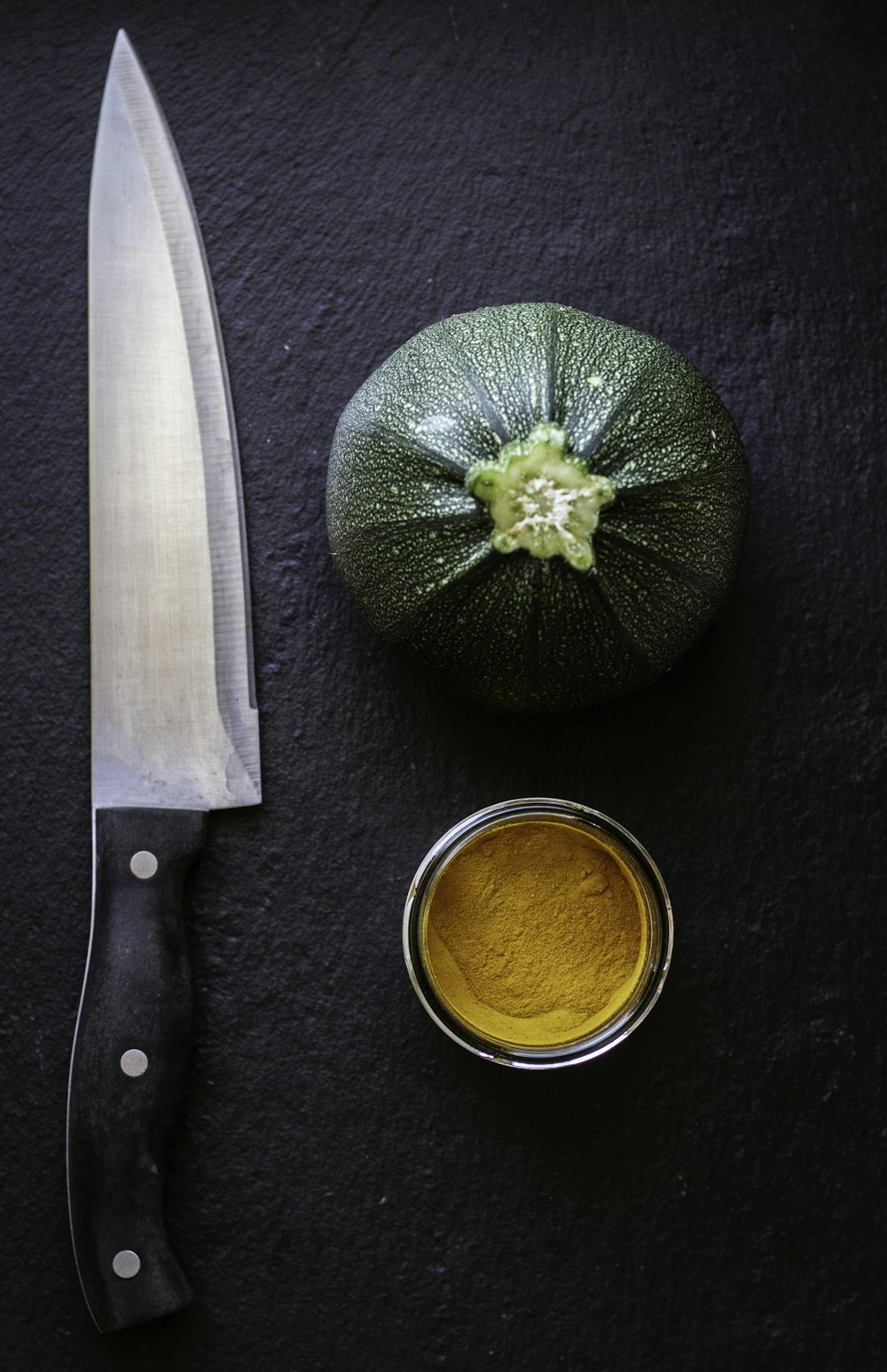 schwarzes Messer mit Griff neben grünem Gemüse