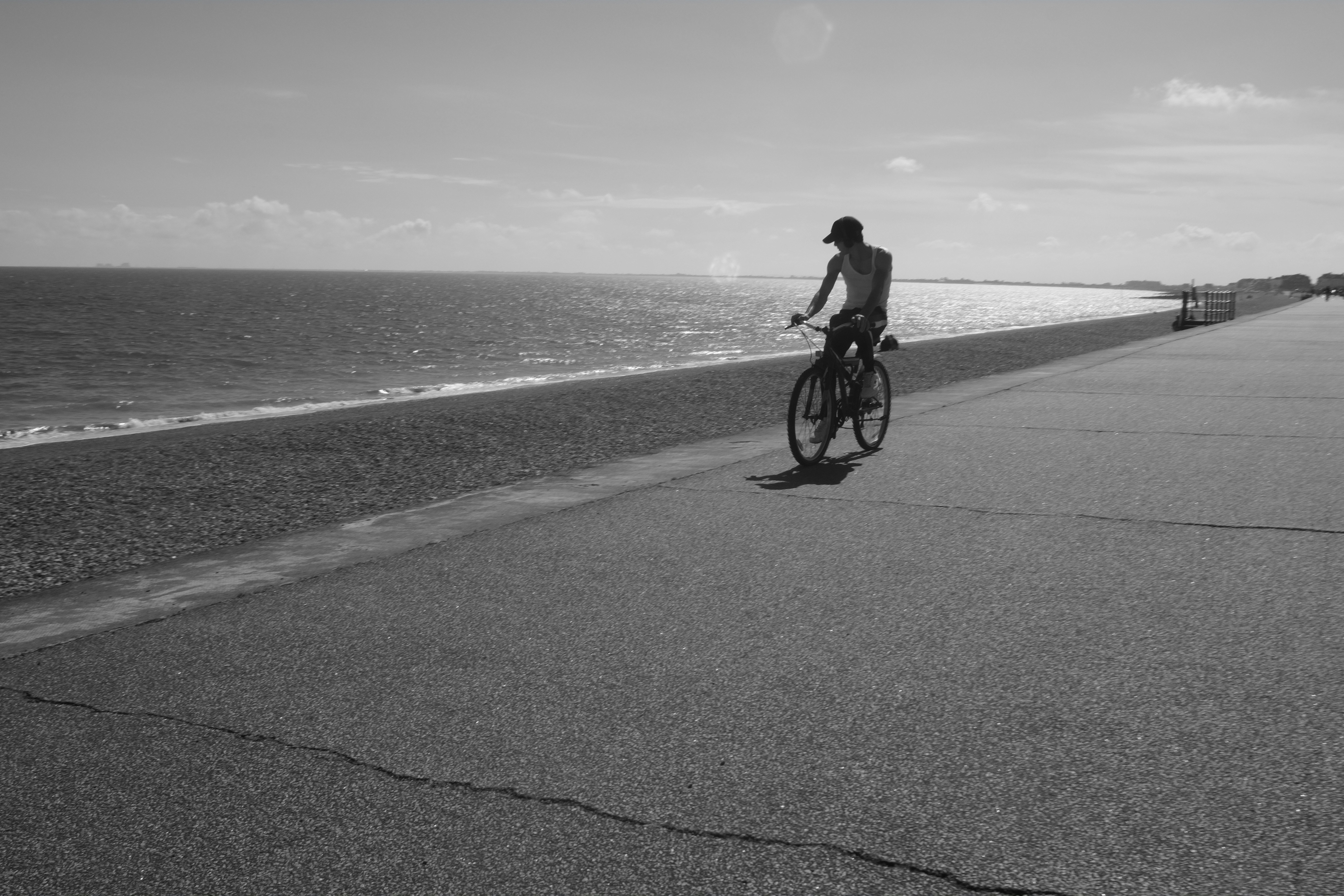 grayscale photo of man riding bicycle on road