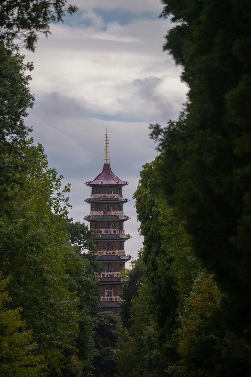 brown and black concrete building surrounded by green trees under white clouds during daytime