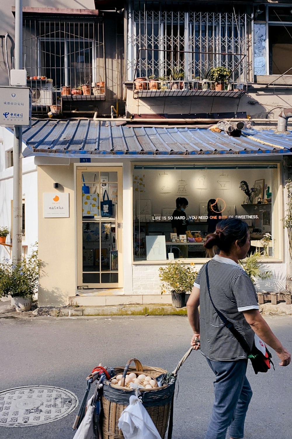 Mujer con camisa de rayas blancas y negras de pie frente a la tienda durante el día