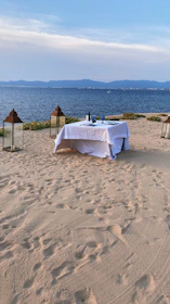 A candlelit table for two on a wooden deck overlooking crystal-clear water and distant islands.