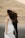 A bride in a white gown appears to be spinning in an outdoor setting, with long hair flowing. A groom in a dark suit stands partially obscured behind her. The background features a dry, grassy hill under soft, diffused lighting.