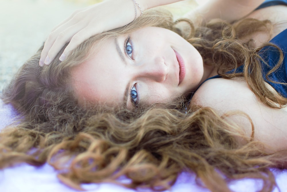 femme en débardeur violet allongée sur textile bleu