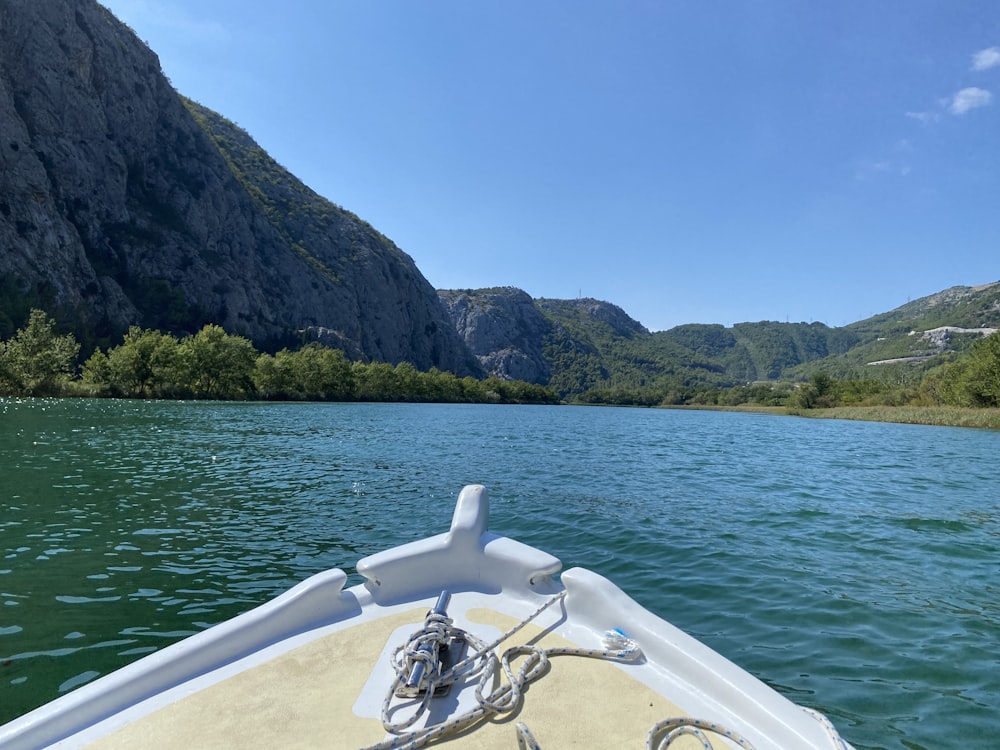 white boat on water near green mountain during daytime