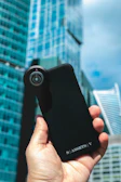Close-up of hands holding a sleek smartphone case from Jalali Nexus with a cityscape background.