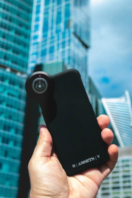 Close-up of hands holding a sleek smartphone case from Jalali Nexus with a cityscape background.