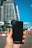 Close-up image of a young woman happily holding sleek gadget accessories in a modern urban setting.