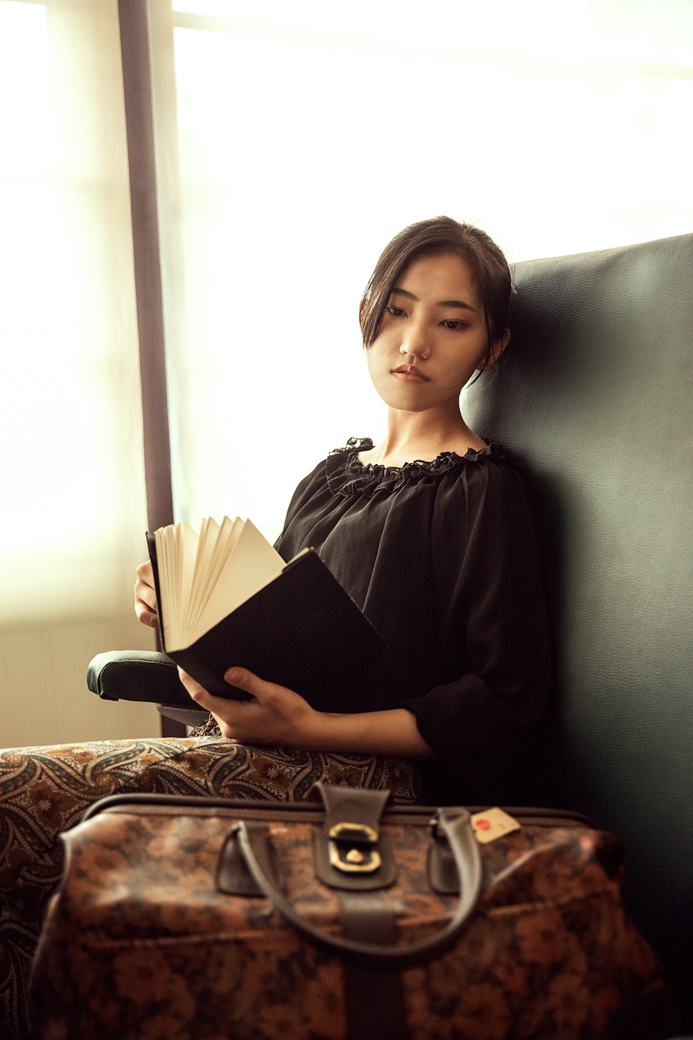 woman in black long sleeve shirt sitting on brown and beige textile