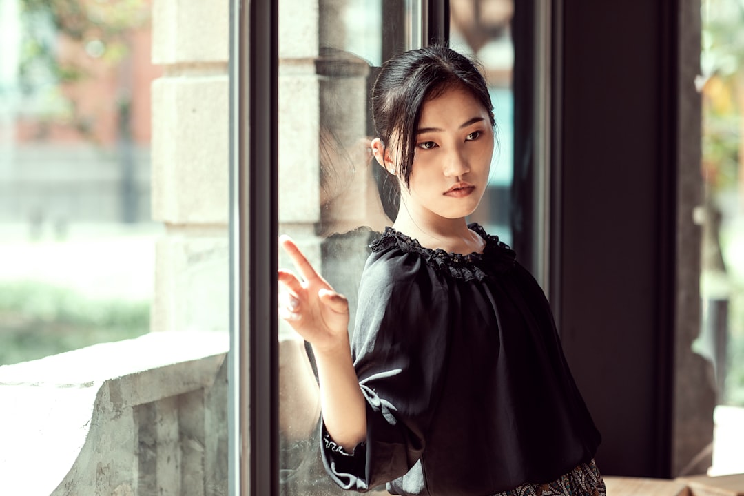 woman in black long sleeve shirt standing beside glass window