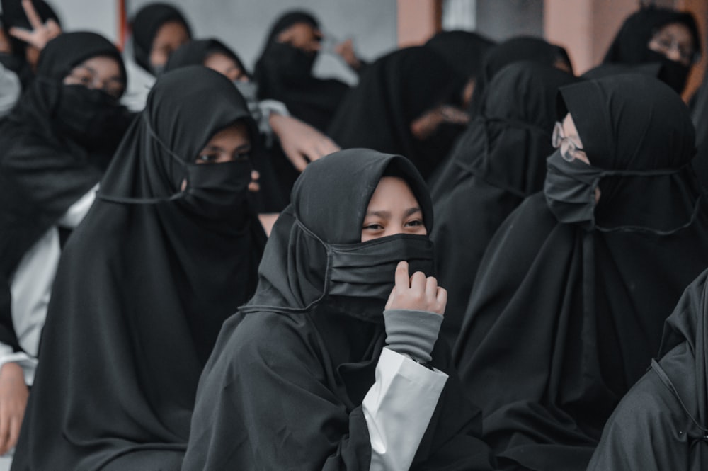 woman in black hijab holding white paper