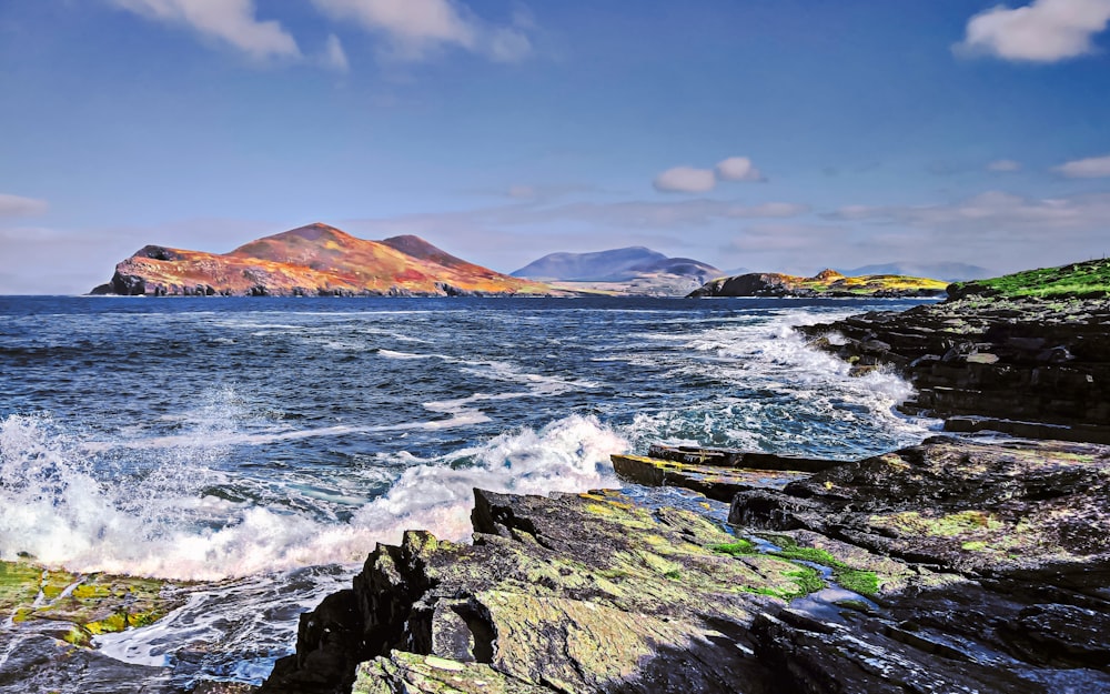 ocean waves crashing on rocks under blue sky during daytime