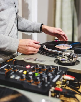 person in gray long sleeve shirt holding black and white dj controller