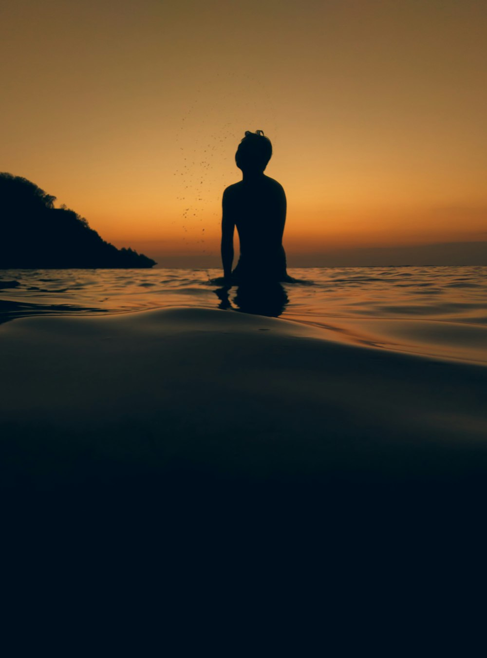 silhouette of man standing on seashore during sunset