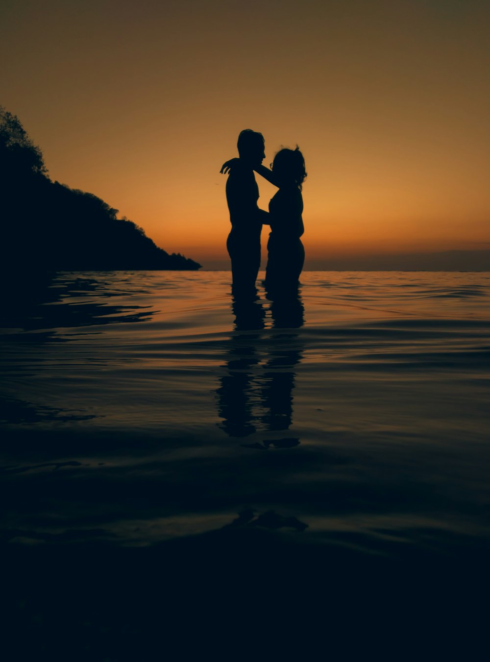 silhouette of man and woman kissing on beach during sunset