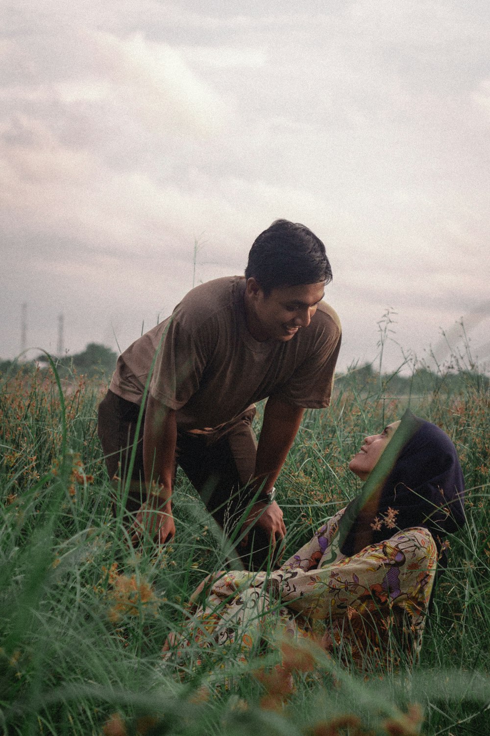 man in brown t-shirt and black pants sitting on green grass field