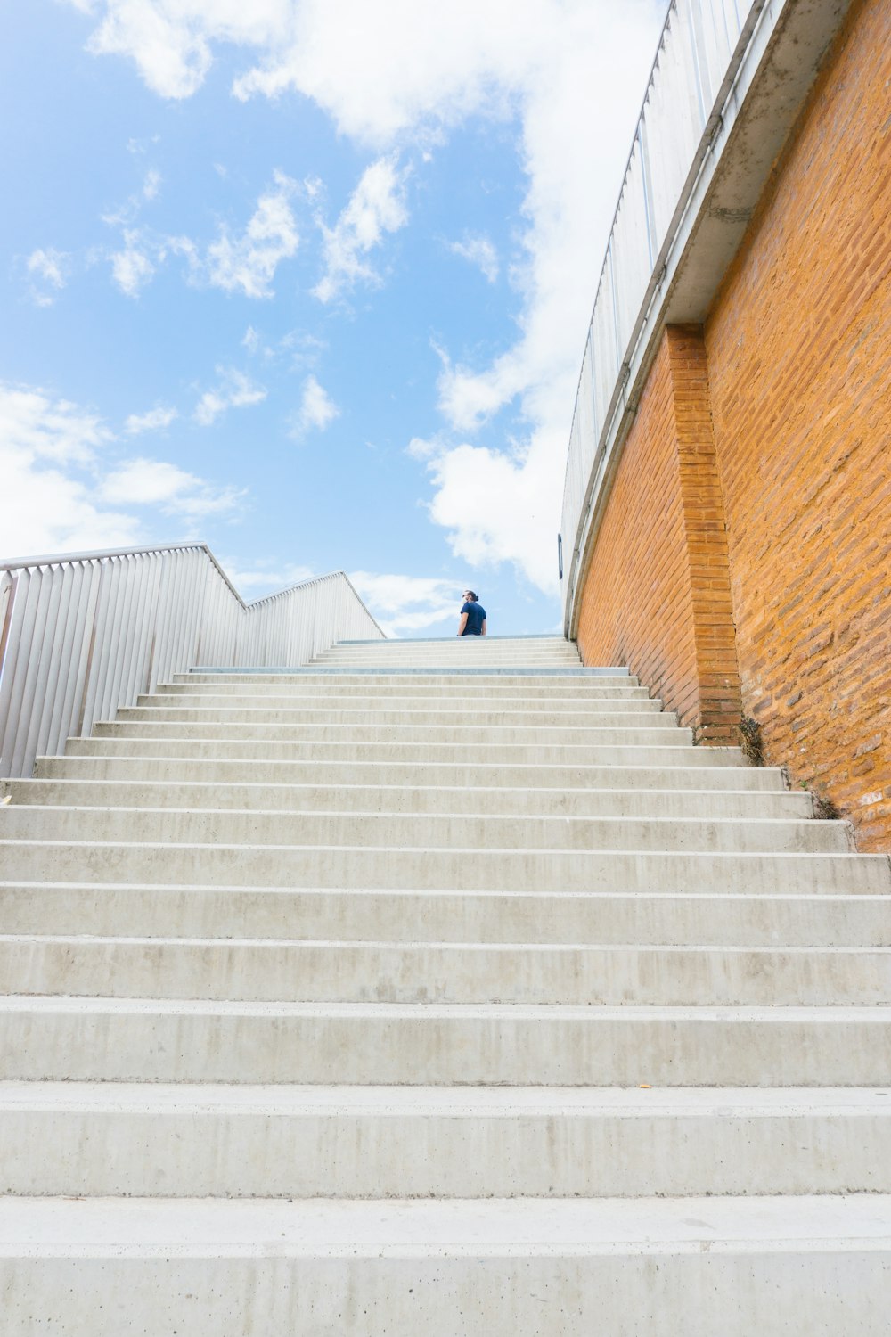 person in black jacket walking on white concrete stairs during daytime
