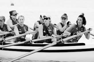 3 women in black and white shirts riding on blue and white boat on sea during